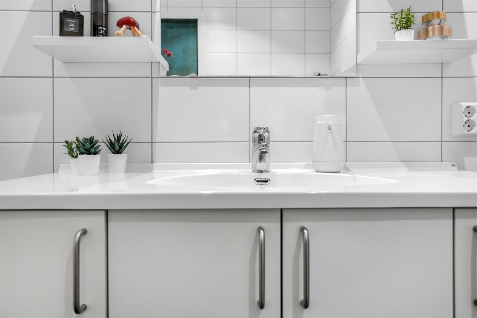 Baderomsinnredningen består av servantbenk med overliggende vegghyller og speil. Under servantplaten er det god oppbevaringsplass i 4-dørs slagdørsskap. Galleribilde