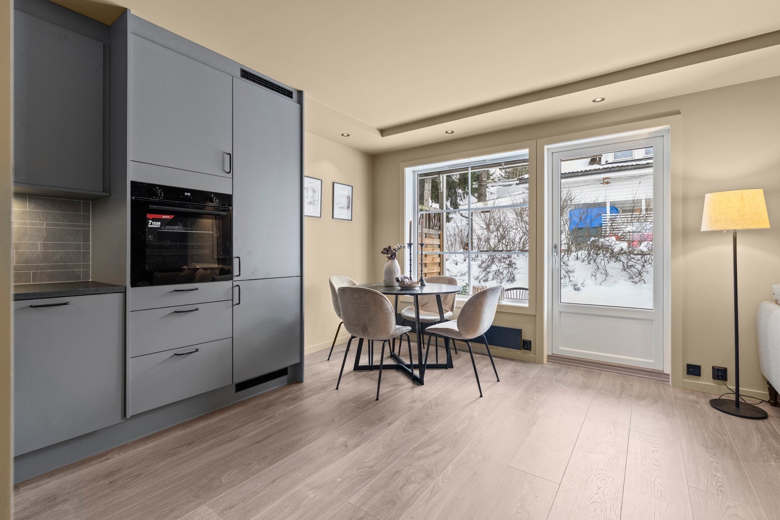 Leilighetens stue og kjøkken ligger i en åpen løsning. Fra rommet er det utgang til en hellelagt uteplass. Galleribilde