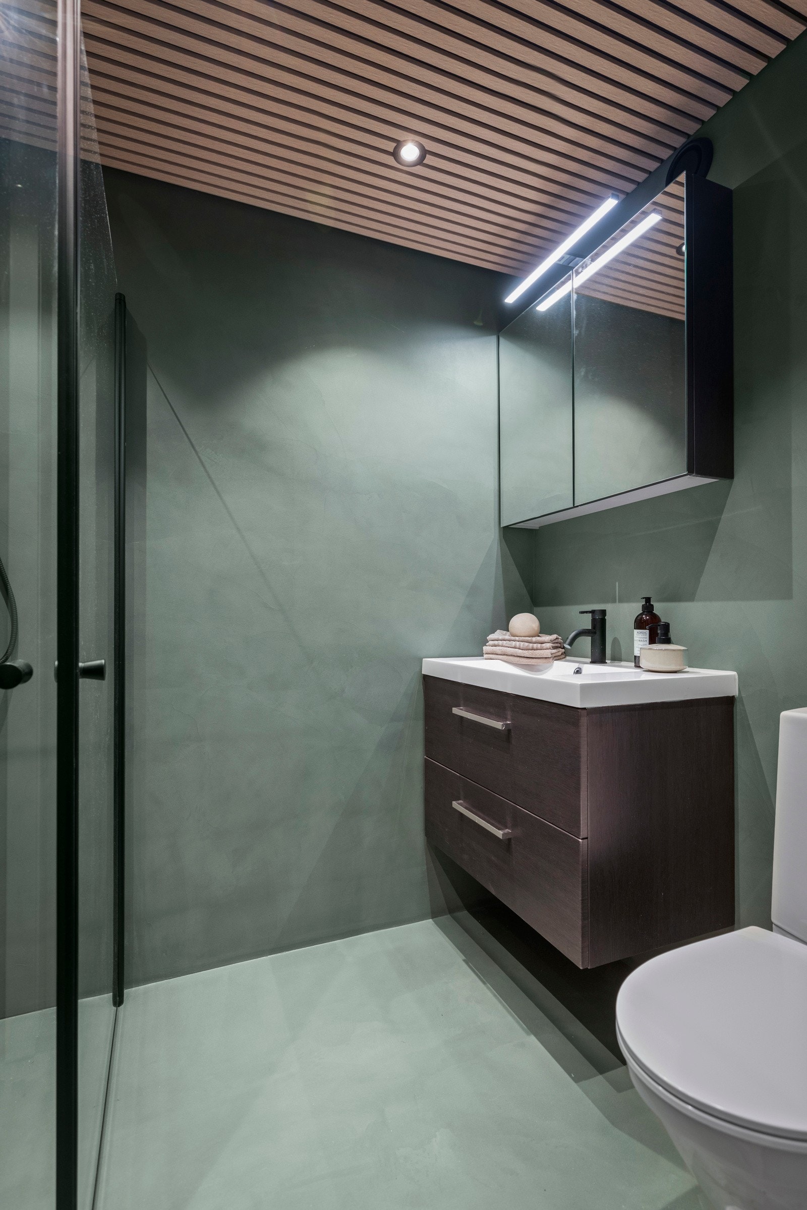 Bad/vaskerommet har opplegg for vaskemaskin, toalett, speilskap med overliggende belysning, baderomsinnredning med finerte fronter og heldekkende servant. Galleribilde