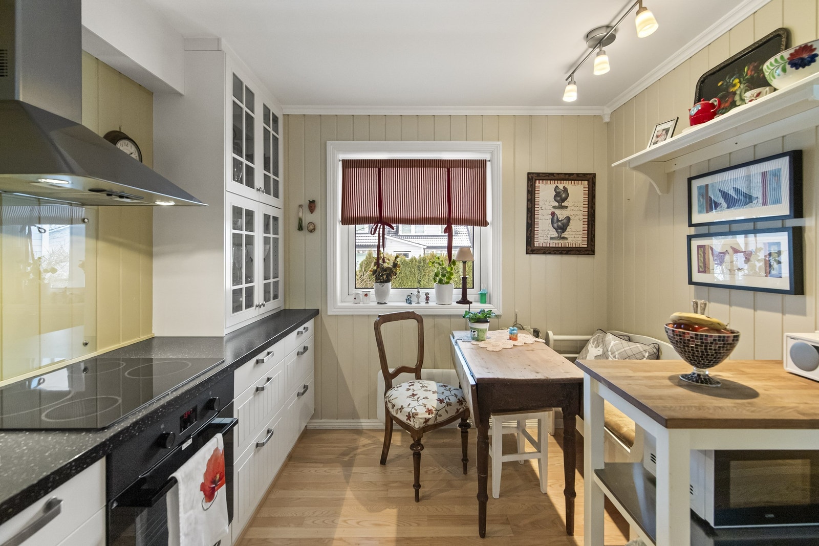 Lyst og trivelig kjøkken med pene gulv og malt panel på vegg Galleribilde