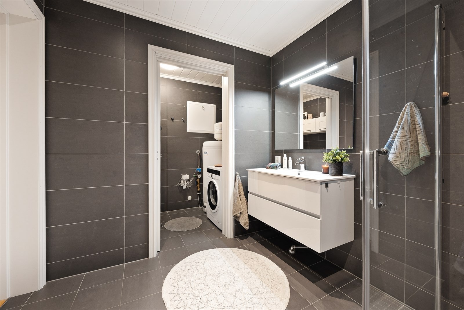 Moderne baderomsinnredning med skuffeseksjon, dusjsone med innfellbare dusjvegger og vegghengt toalett. Galleribilde