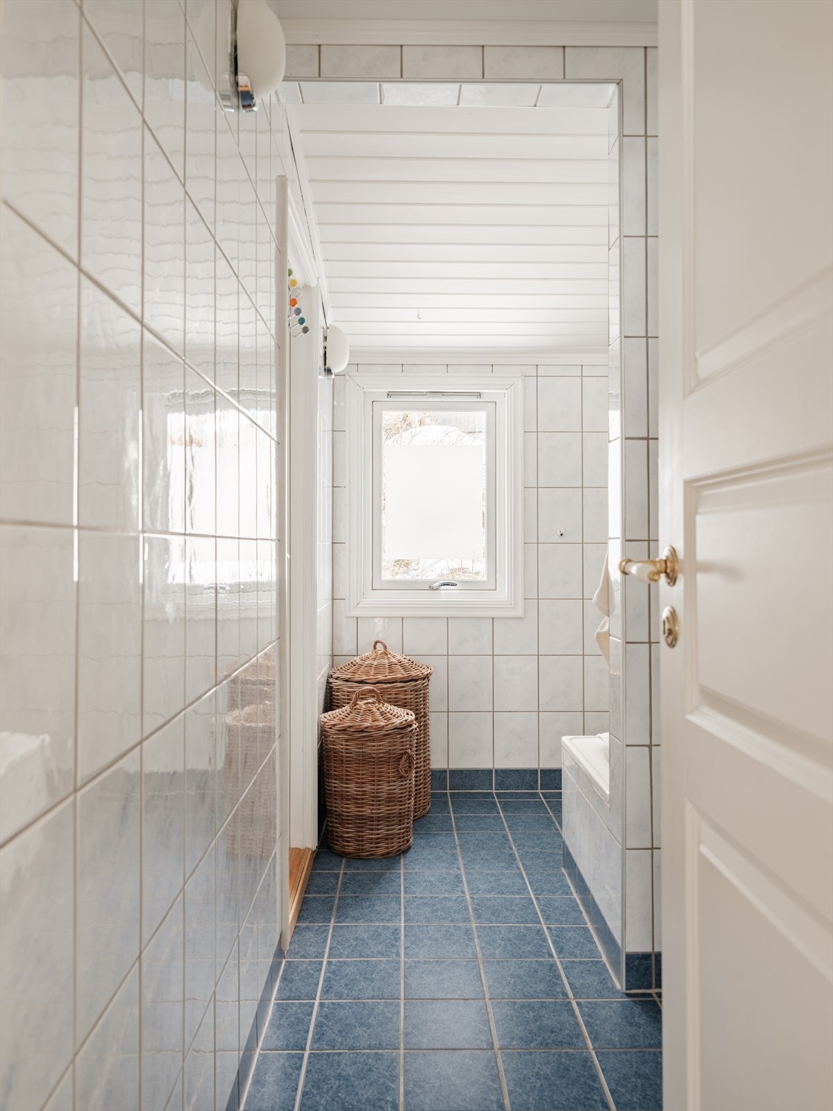 Romslig baderom fra 2002 med flislagt gulv med gulvvarme, flislagte vegger og himling med malt panel. Innredningen består av vegghengt servant med ettgreps armatur og speilskap med overlys og stikkontakt. Galleribilde