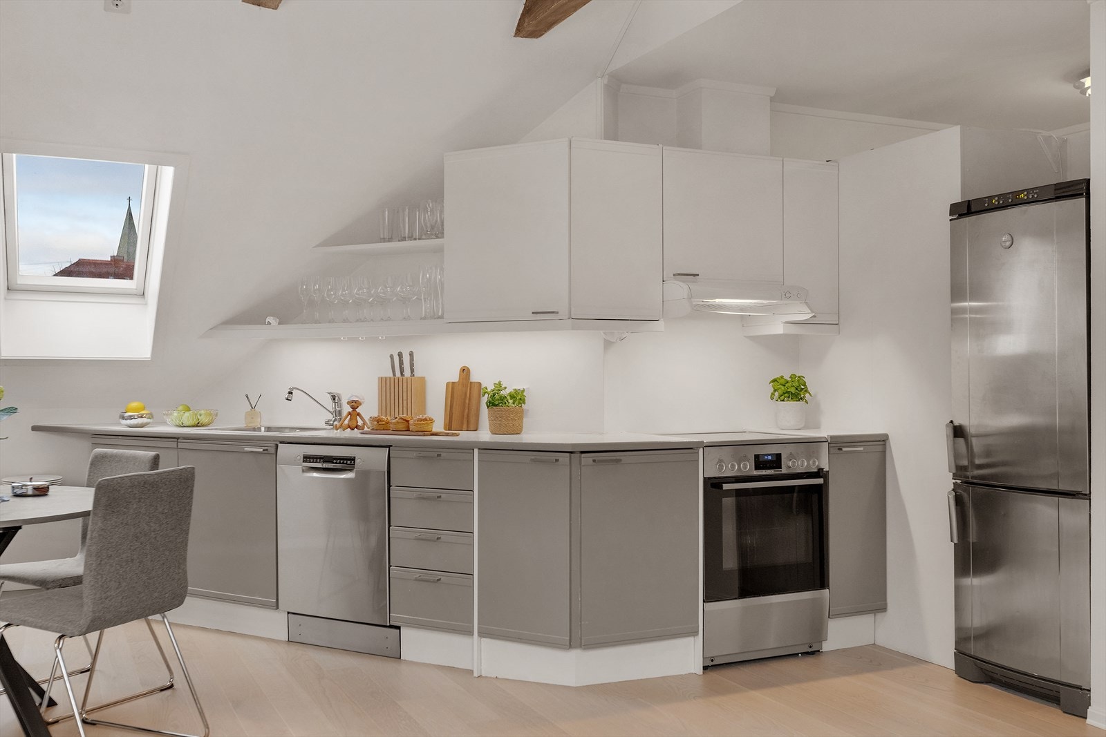 Kjøkkenet har profilerte fronter i hvitt og grått som gir et klassisk og rolig uttrykk, og den laminerte benkeplaten har malte flater over for et helhetlig preg. Galleribilde