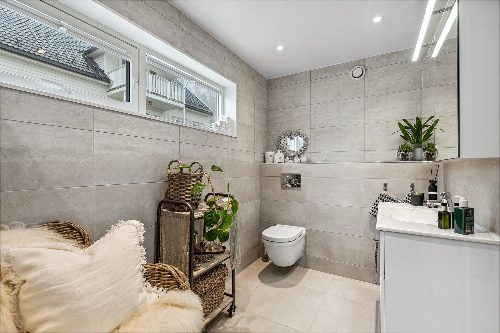 Flislagt bad i boligens andre etasje med varmekabler i gulv og downlights i himling. Innredet med vegghengt toalett, moderne servantløsning med speilskap og praktisk oppbevaringsplass. Galleribilde