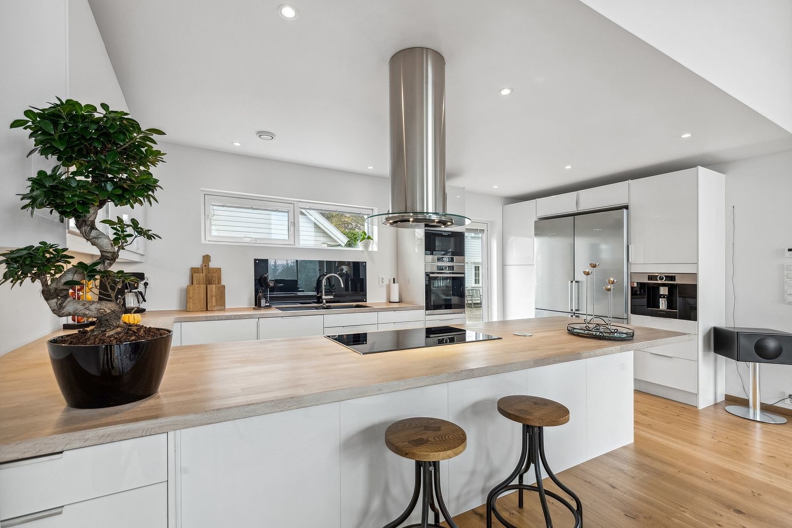 Moderne kjøkken med slette, hvite fronter og integrerte hvitevarer. Praktisk layout med god arbeidsplass og naturlig lysinnslipp. Galleribilde