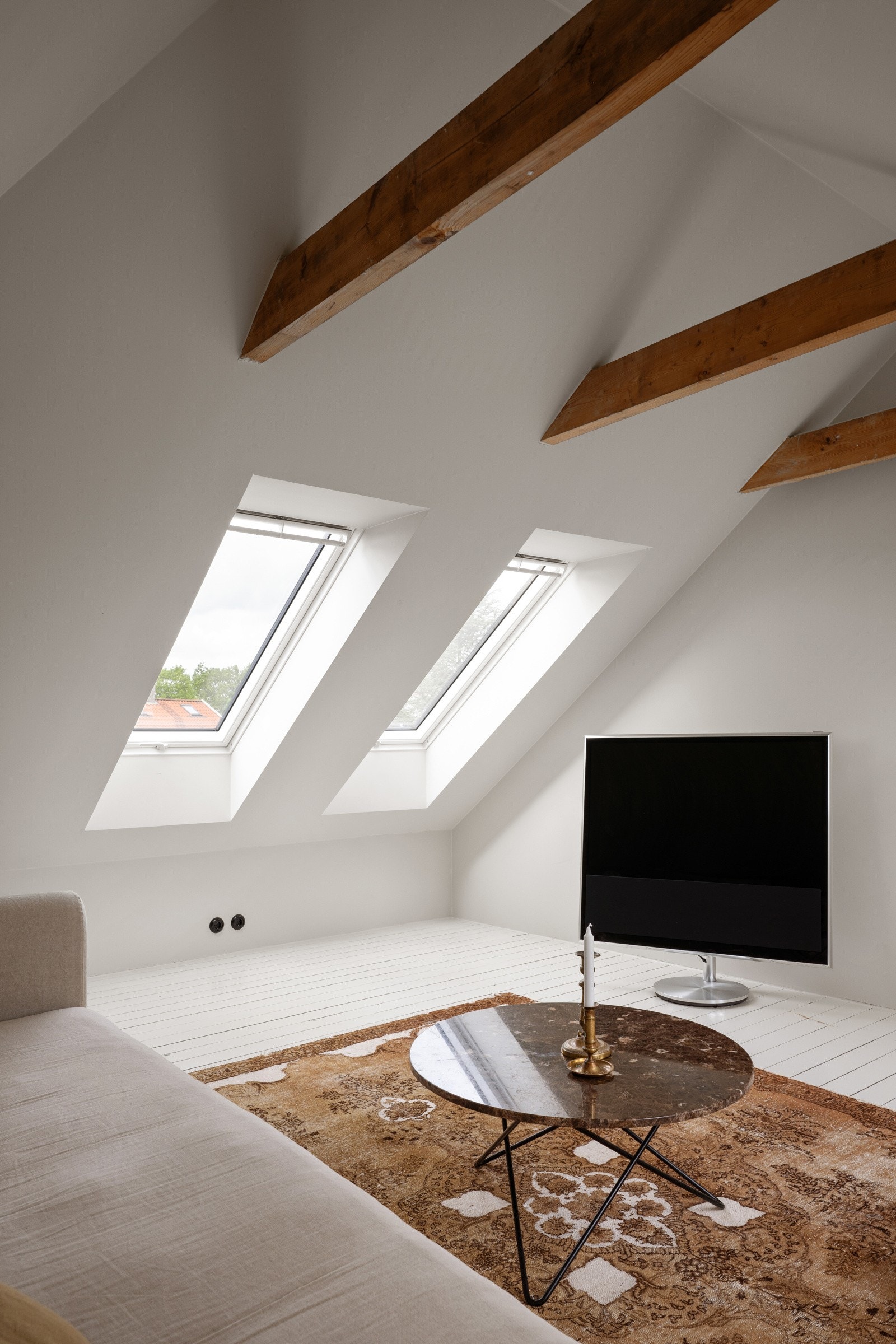 Rommet har malte tregulv og synlige bjelker i fin kombinasjon med lysmalte, slette vegger. Galleribilde