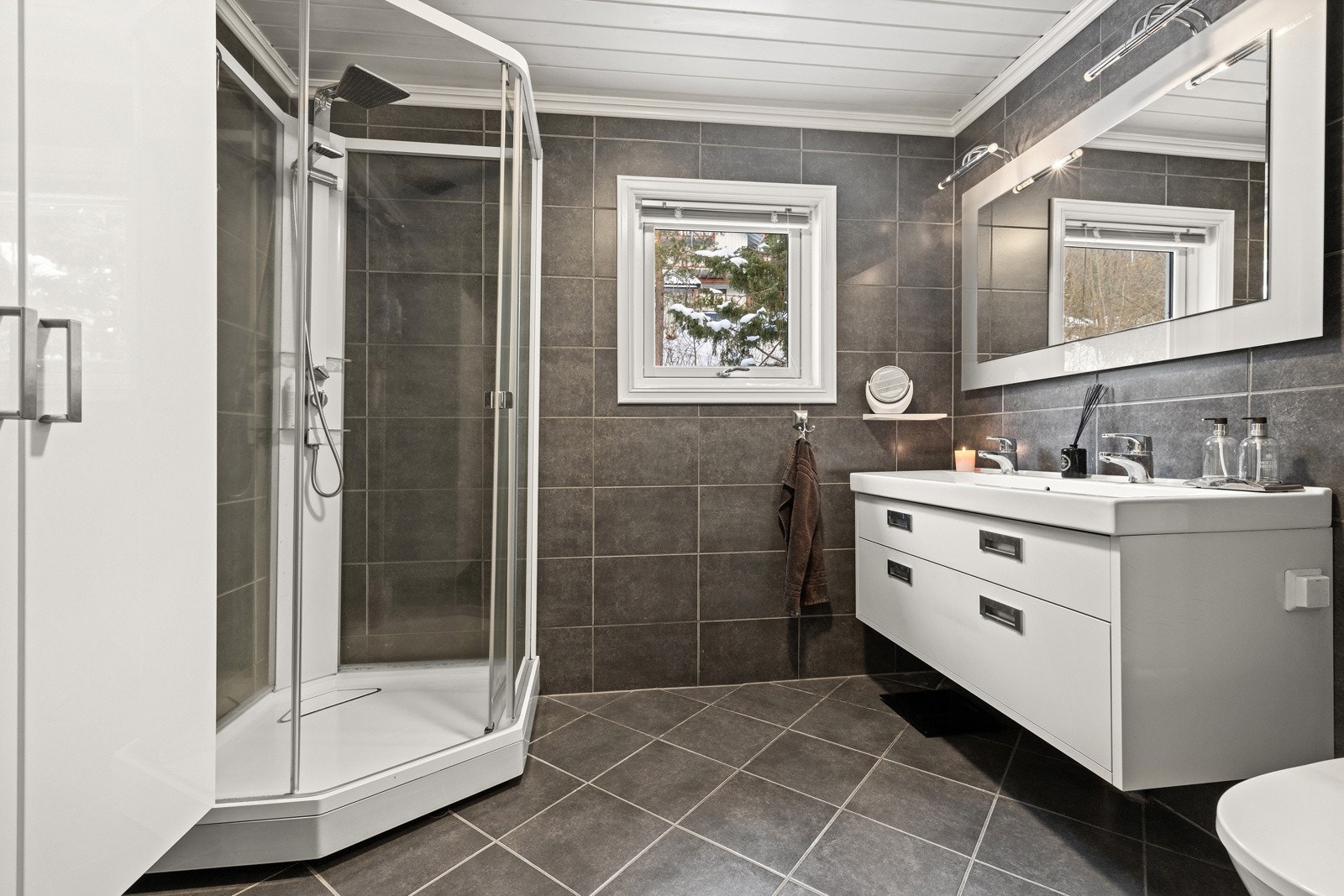 Delikat og flislagt bad med dusjkabinett, servantinnredning og god oppbevaringsplass. Galleribilde