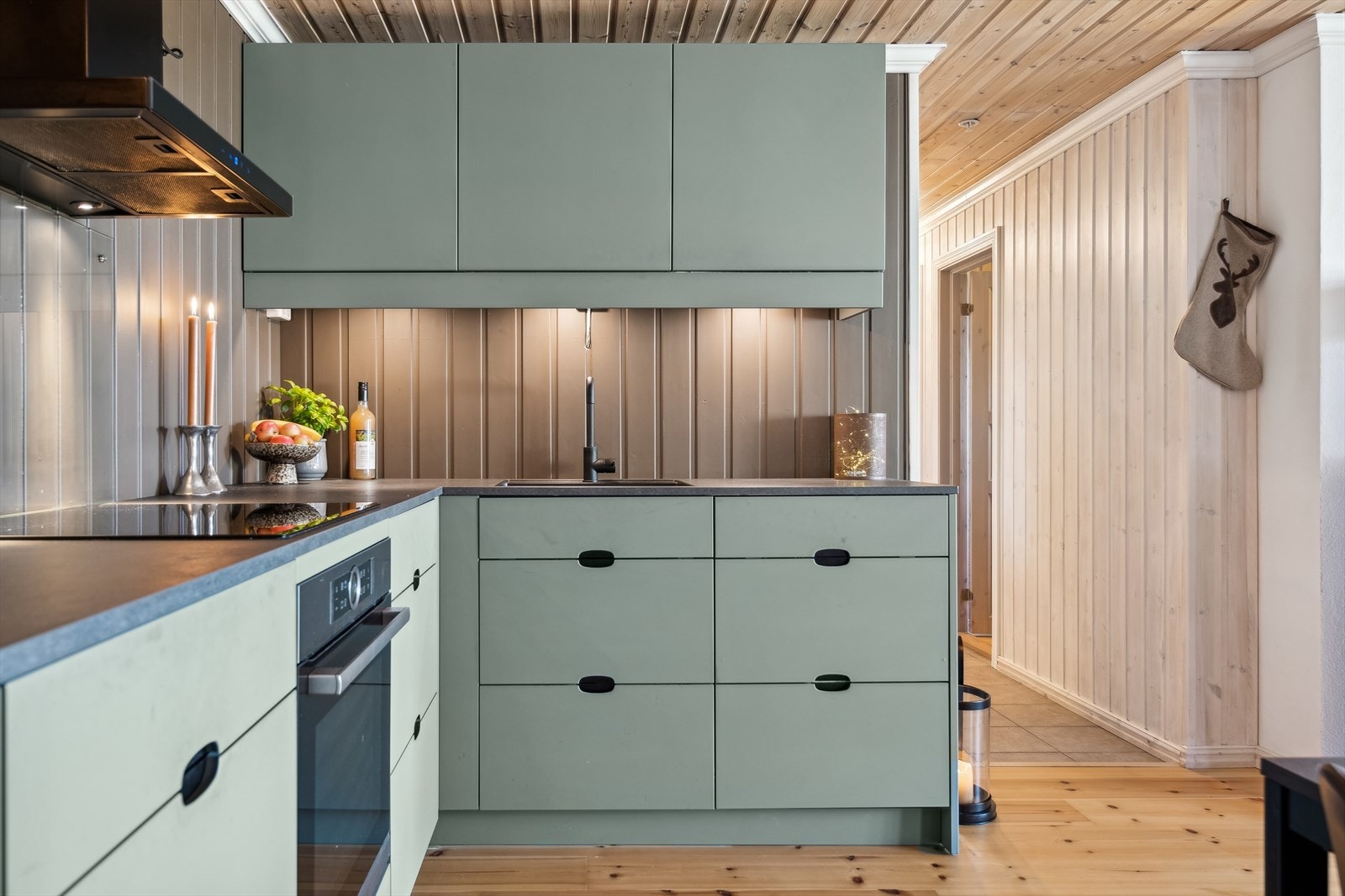 Kjøkkeninnredningen er holdt i en elegant olivengrønn farge som tilfører varme og personlighet til rommet, samtidig som det skaper en harmonisk og moderne atmosfære. Galleribilde