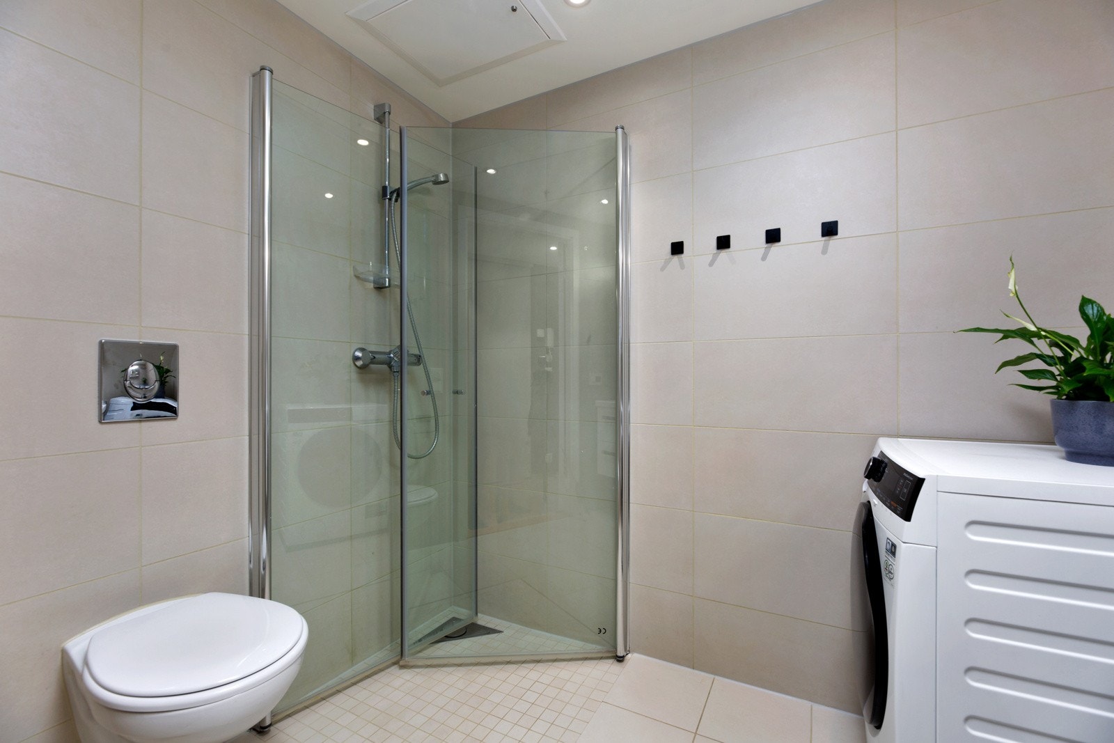 Nedsenket dusjhjørne med innfellbare glassdører og vegghengt toalett. Opplegg for vaskemaskin. Galleribilde