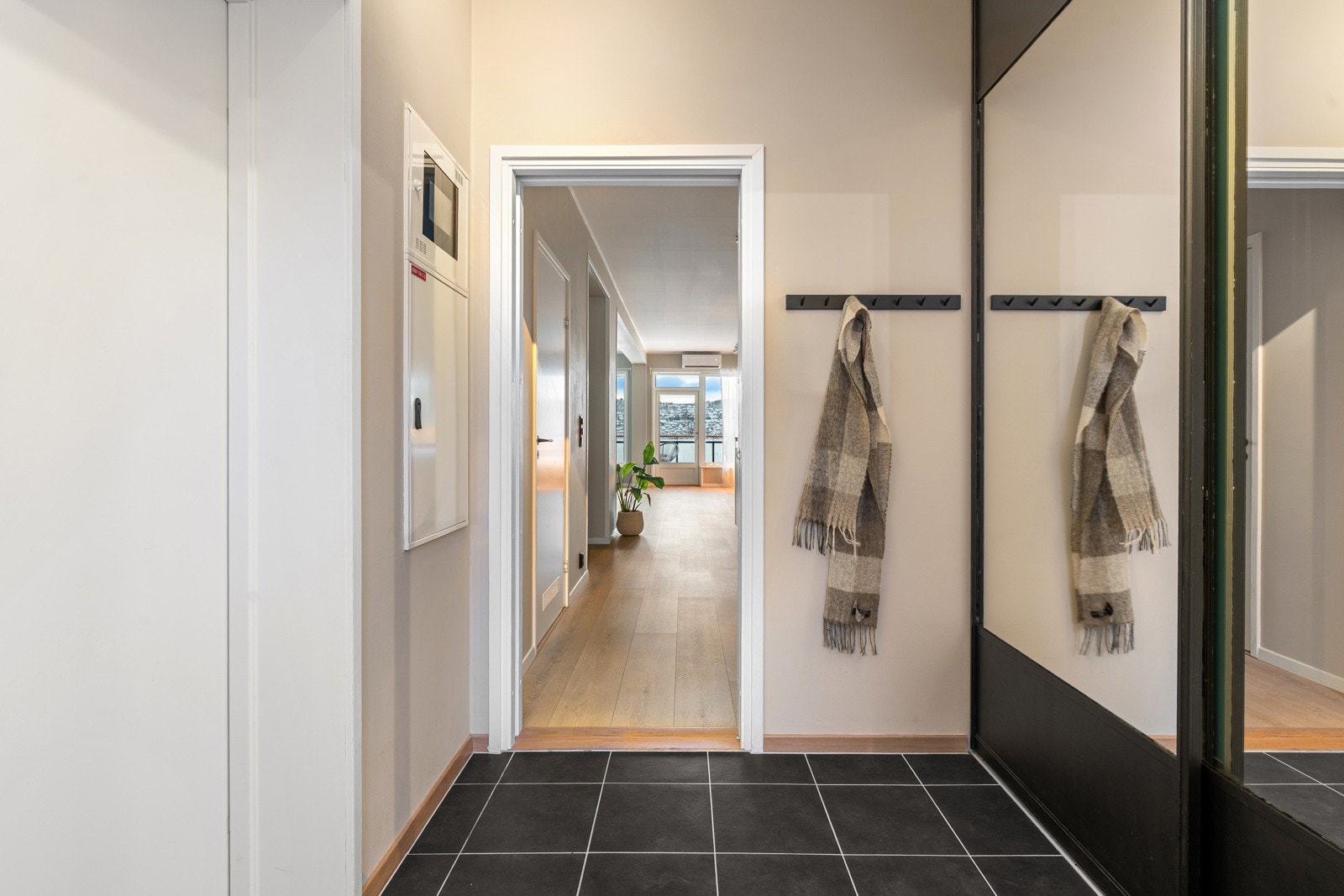 Romslig entre med fliser på gulv, gulvvarme og en stor skyvedørsgarderobe