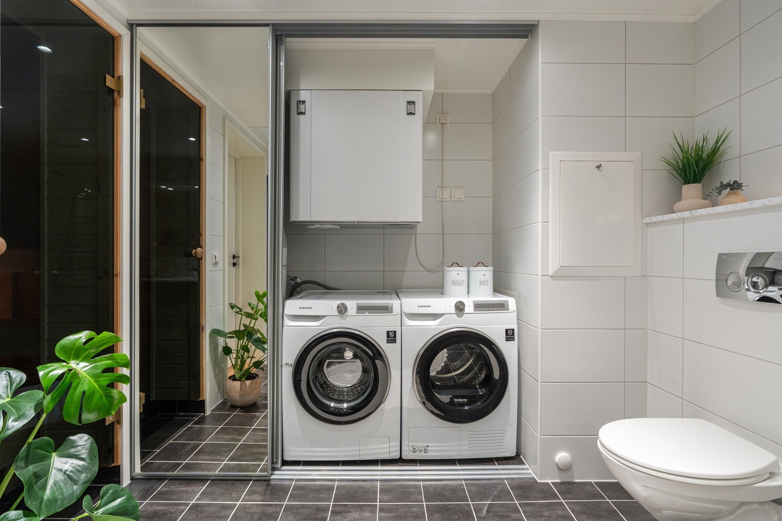 Opplegg for vaskemaskin skjult bak skyvedørene. Her er det også ekstra lagringsplass