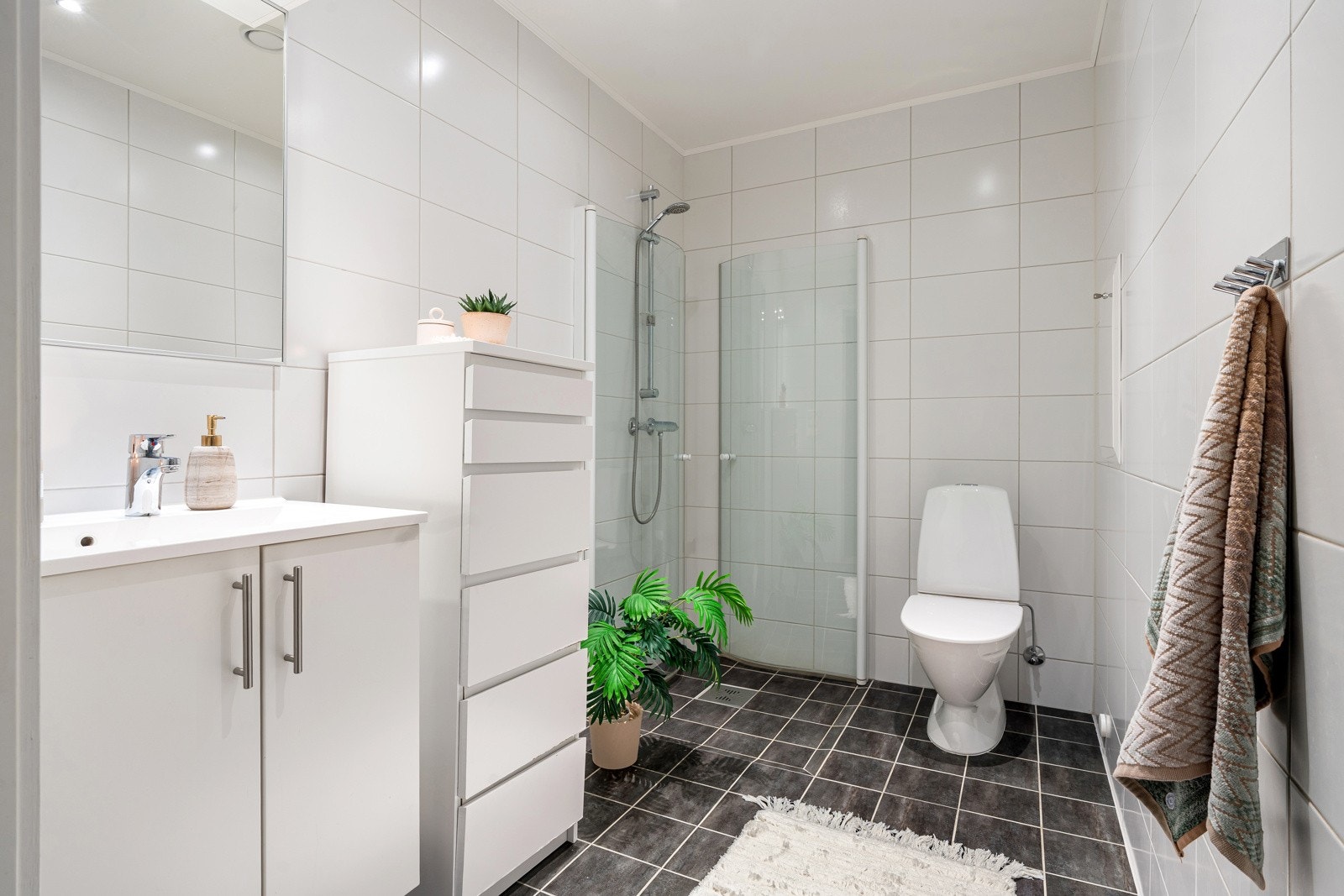 Badet har wc, lys baderomsinnredning og dusjhjørne med innfellbare glassdører.