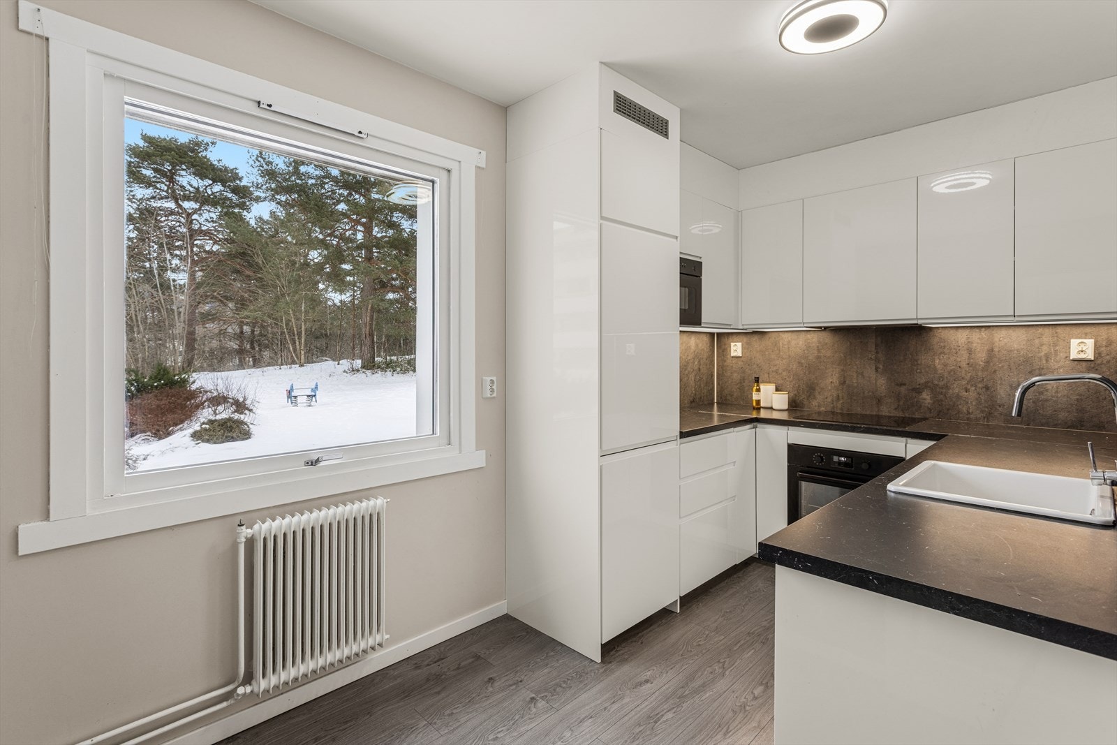 Delikat kjøkken fra 2020 med glatte fronter og en benkeplate i laminat. Plass til spisebord. Galleribilde