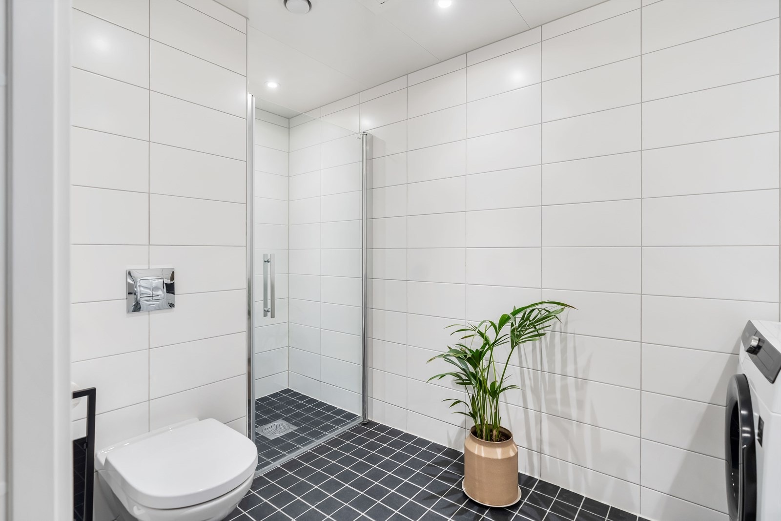 Videre er badet utstyrt med rørfordelingsskap, stoppekran, mekanisk avtrekk, opplegg for vaskemaskin, dusjnisje, veggmontert wc og servantskap med ett greps blandebatteri fra Gustavsberg. Galleribilde