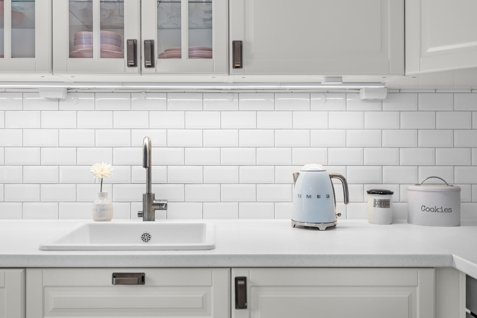 Det er profilerte folierte fronter, laminat benkeplate med nedfelt kum i keramikk og lyslist montert under overskap. Galleribilde