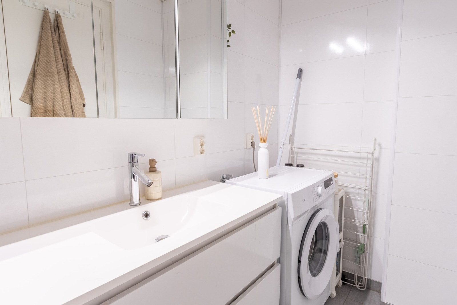 Badet er innredet med varme i gulv, servantinnredning, dusjhjørne med innfellbare glassdører og opplegg for vaskemaskin Galleribilde