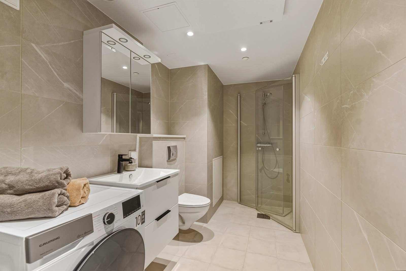 Baderommet er svært delikat utført, med marmorerte fliser på vegg og gulvfliser som går ton-i-ton og bidrar til et sømløst uttrykk. Galleribilde