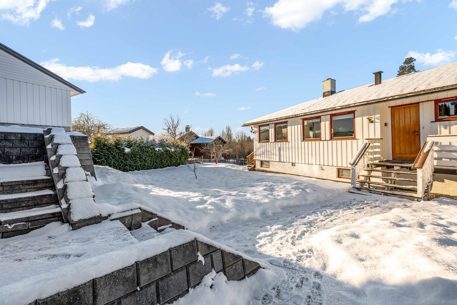 Det er trapp og støttemur fra garasjen og parkeringsplassen ned til hagen og inngangspartiet Galleribilde