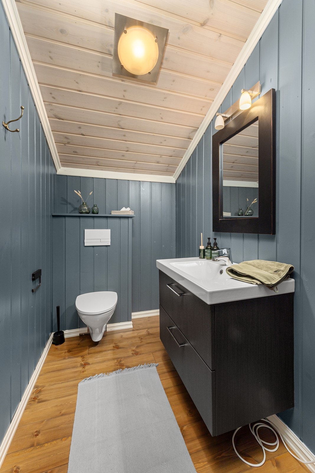 Toalettrom i oppstue med servant, skuffer, speil og vegghengt toalett. Galleribilde