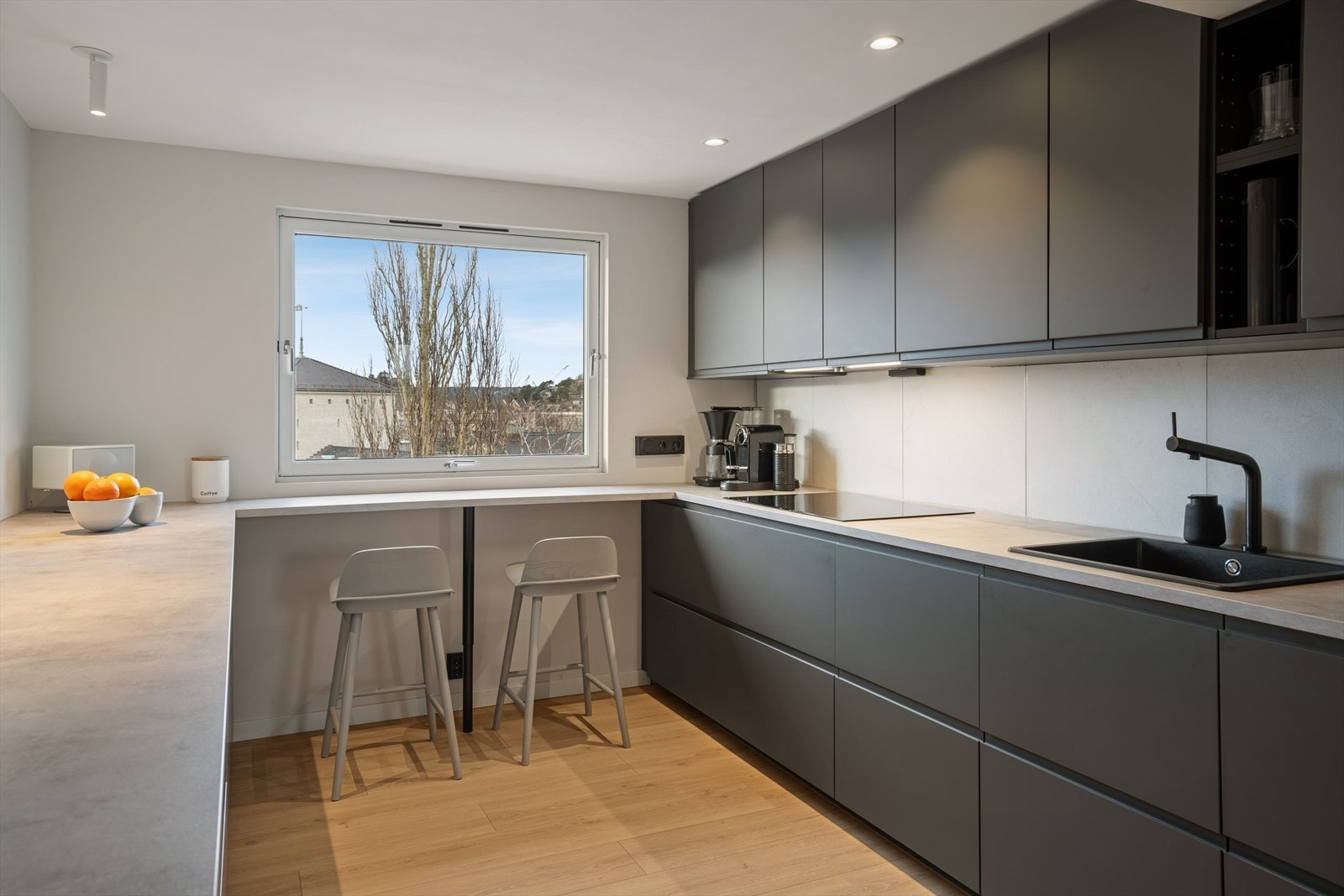 Innredningen har slette, grå fronter og en laminert benkeplate med oppvaskkum og kjøkkenkran. Galleribilde