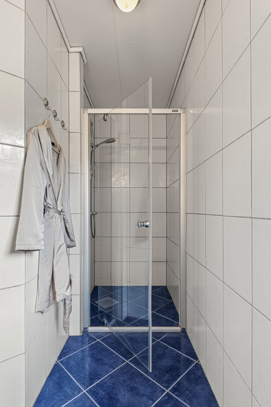 Badet er innredet med innredning med nedfelt servant, dusjhjørne med glassvegger og toalett. Badet har en elektrisk vifte i taket og luftespalte i dør. Galleribilde