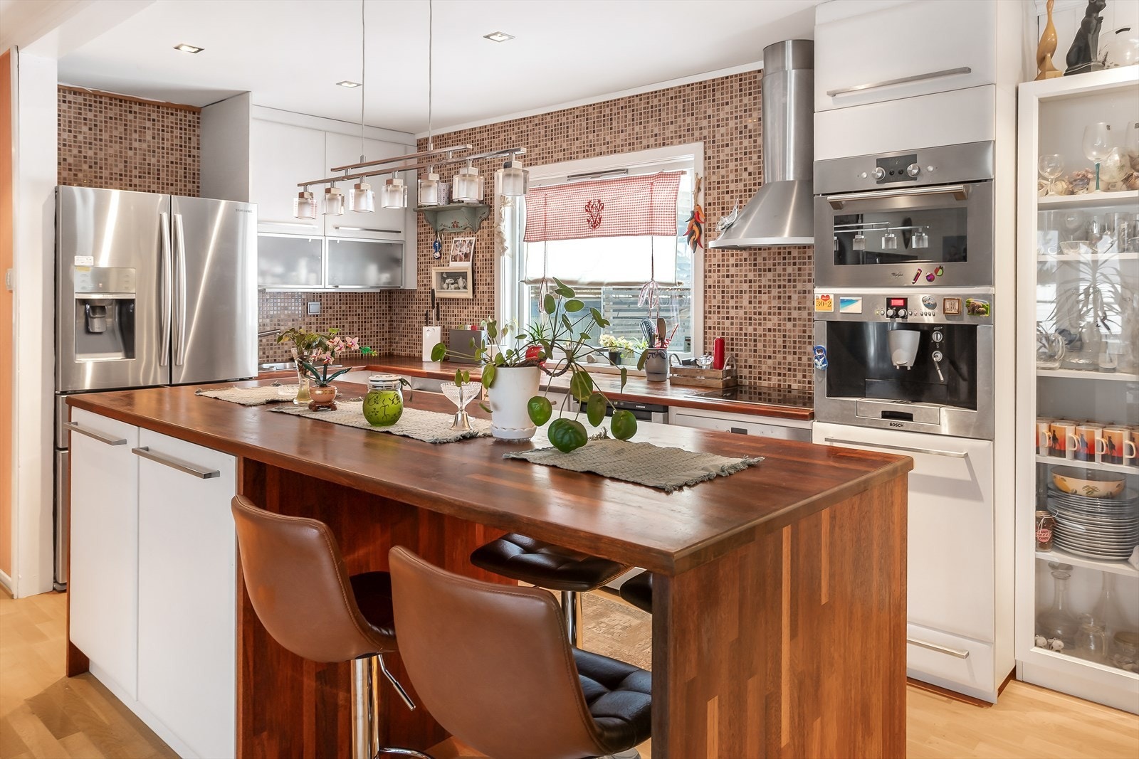 Kjøkkeninnredning med slette fronter. Heltre benkeplate med fliser over benk. Galleribilde