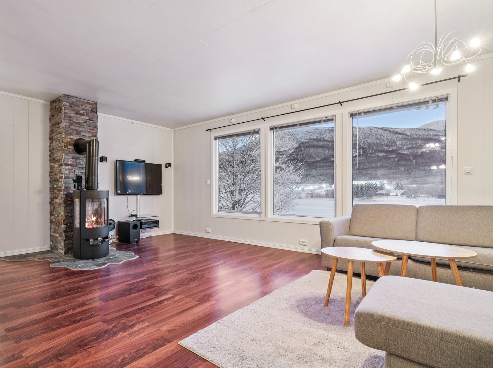 En sentralt plassert peisovn med steinbelagt pipe gir både varme og karakter til rommet. Galleribilde