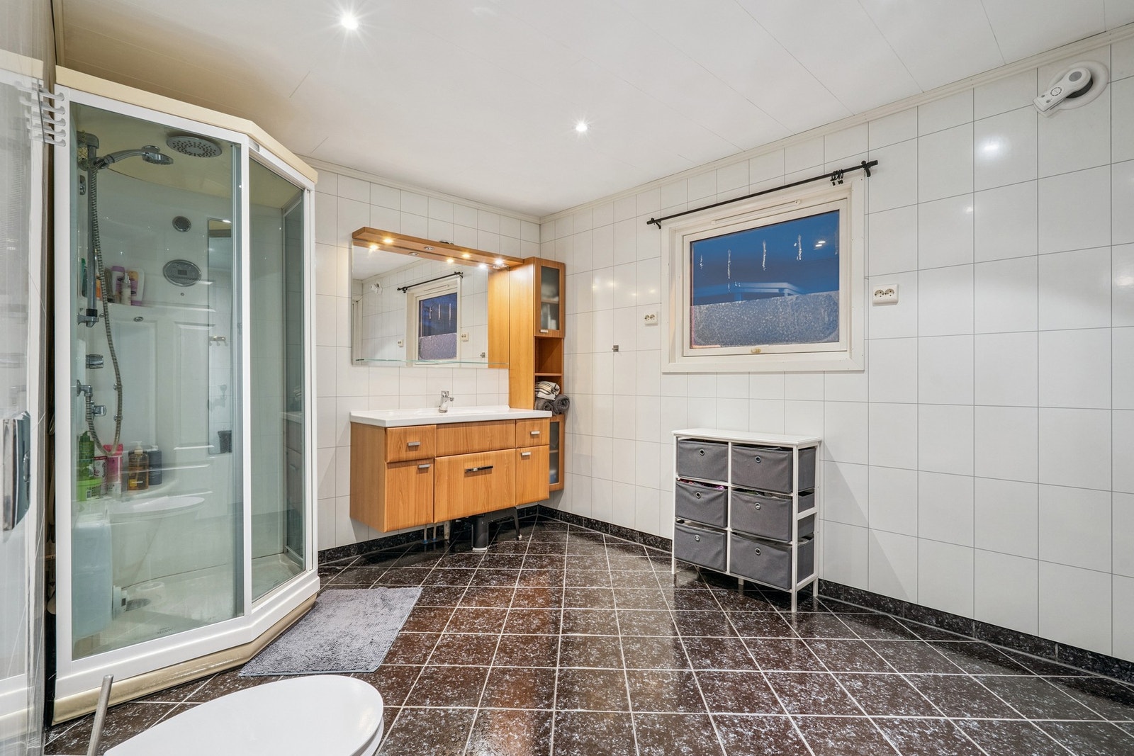 Rommet er innredet med en stor baderomsinnredning med servant og et dusjkabinett. Galleribilde