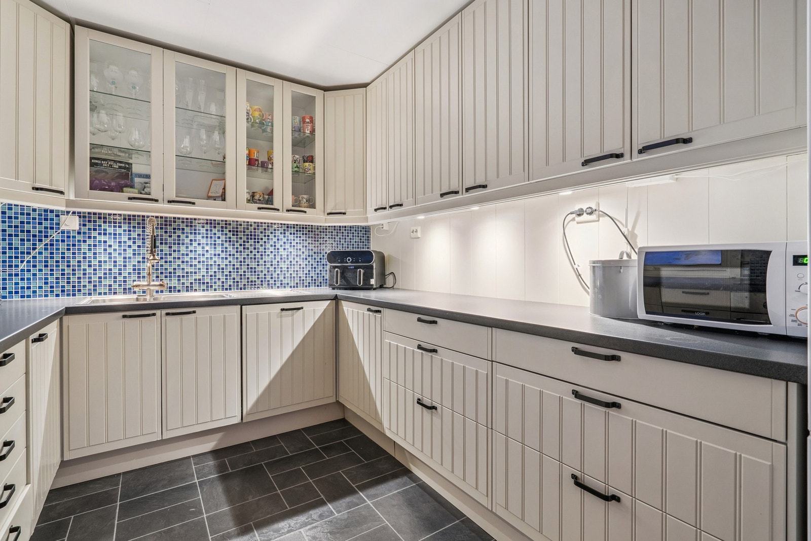 Overskap med vitrinedører og god belysning under gir et funksjonelt arbeidsområde. Galleribilde