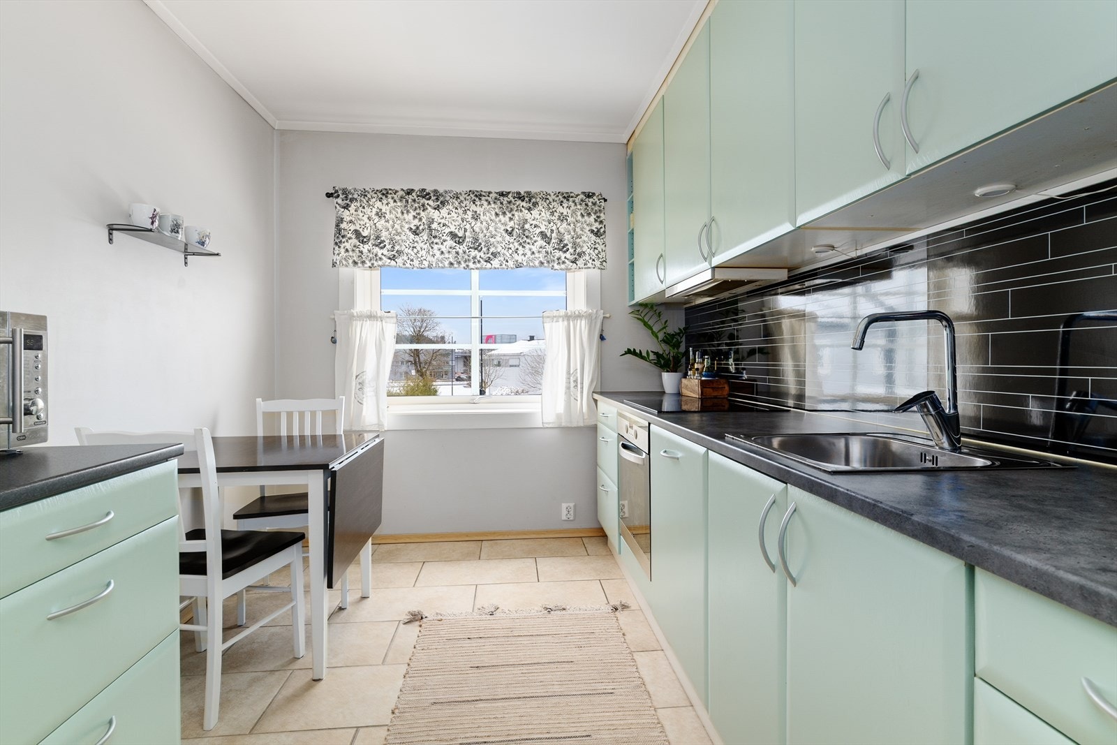 Pent kjøkken med takhøy kjøkkeninnredning og hyggelig spiseplass. Innredningen har godt med skapplass, integrert oppvaskmaskin og stekeovn. Galleribilde