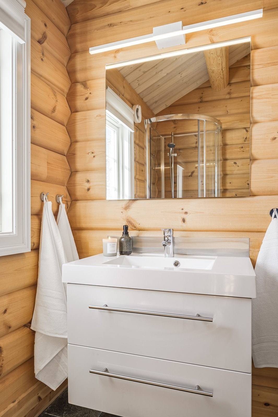 Badet er innredet med servant på innredning, dusjkabinett og vegghengt toalett. Galleribilde