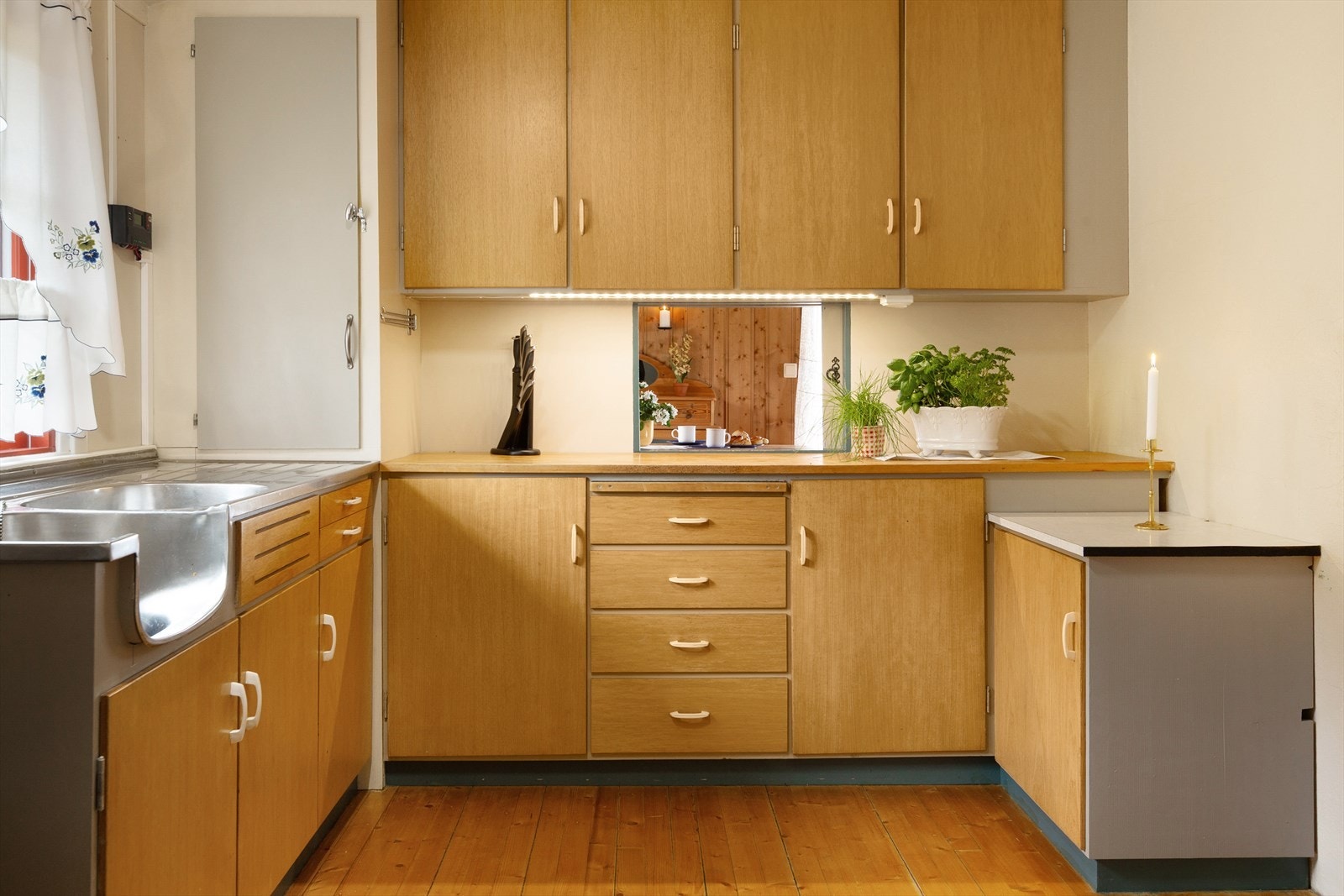 Kjøkkenet har innredning fra byggeår med finerte glatte fronter, heltre benkeplate på hovedbenk og laminert benkeplate på sidebenk. Galleribilde