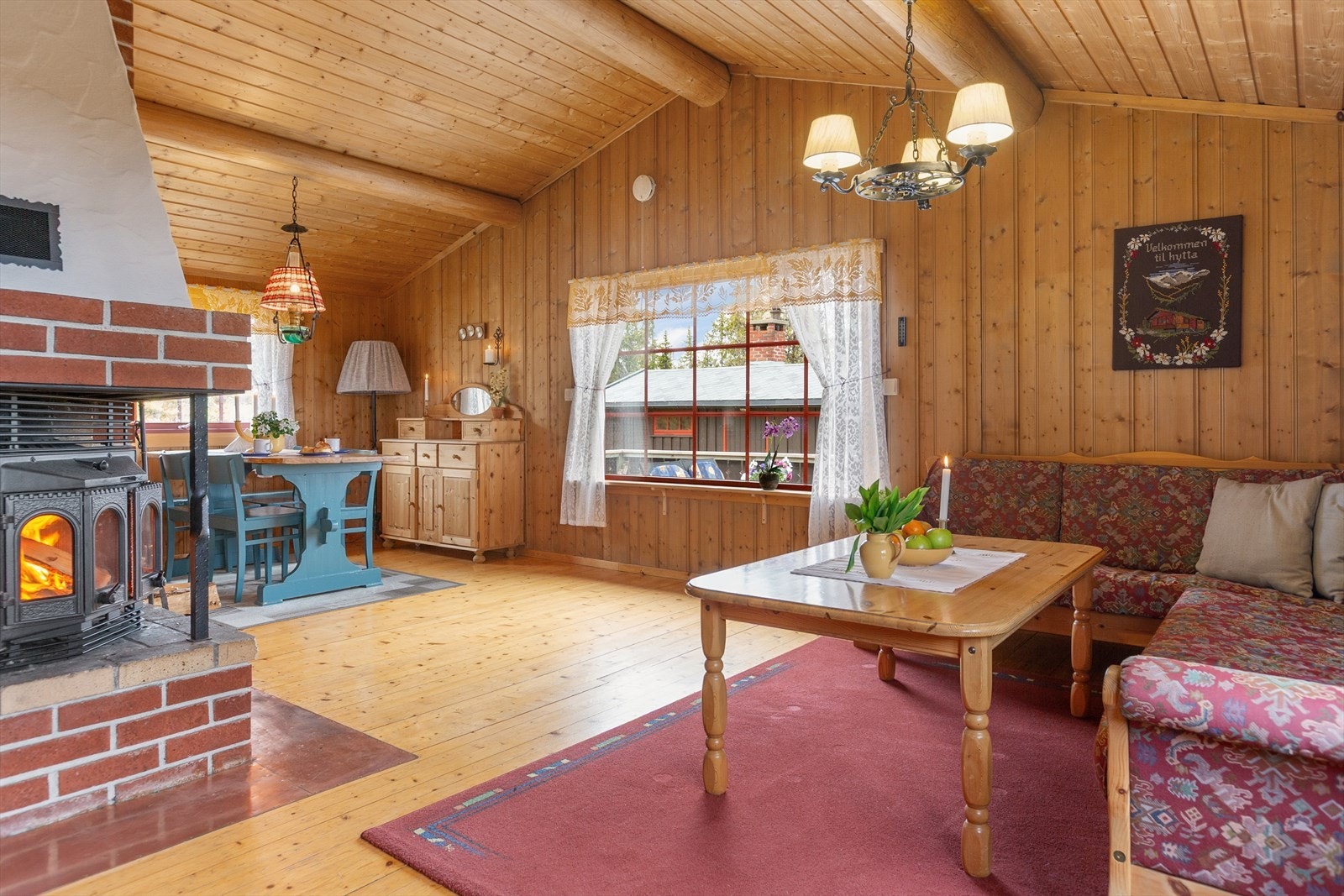 Inne i hytta er det lyst og trivelig med mange vinduer og mønet himling med tømmeråser i stue. Galleribilde