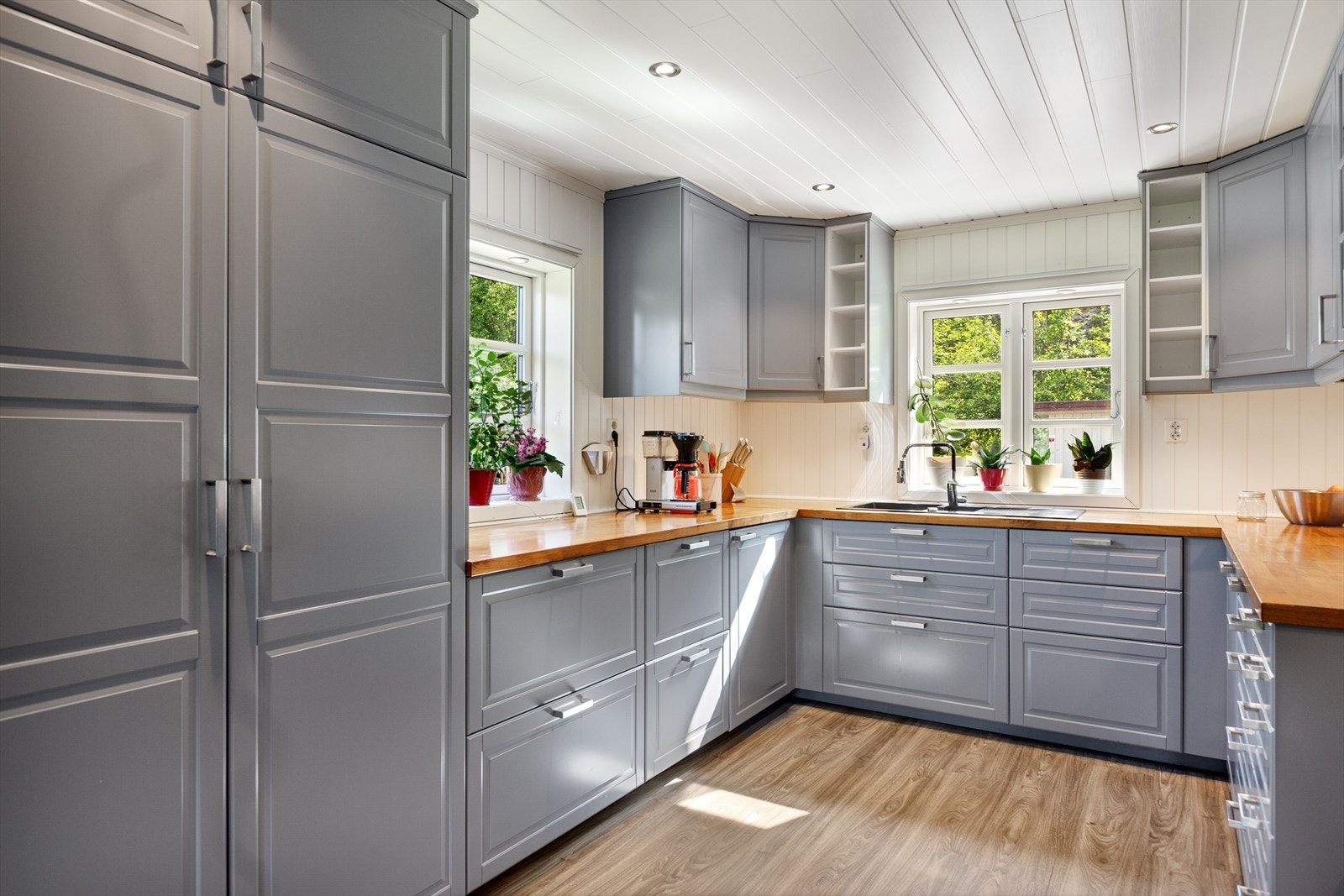 Kjøkkeninnredningen har malte profilerte fronter i formpresset materiale og heltre benkeplate med oppvaskkum i kompositt. Galleribilde