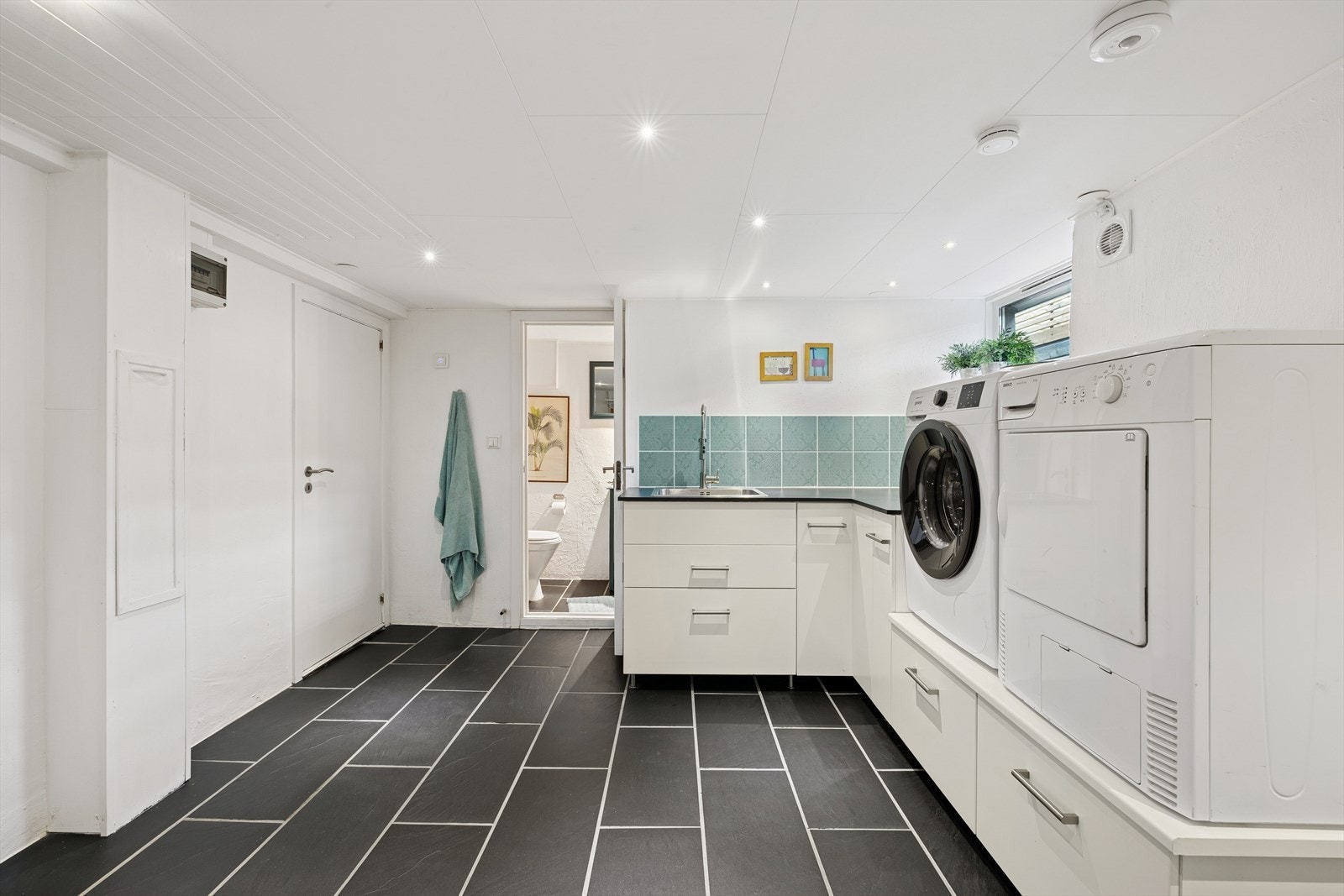 Vaskerommet er innredet med underskap, laminert benkeplate, nedfelt skyllekar, samt tappekran og avløp for vaskemaskin. Galleribilde