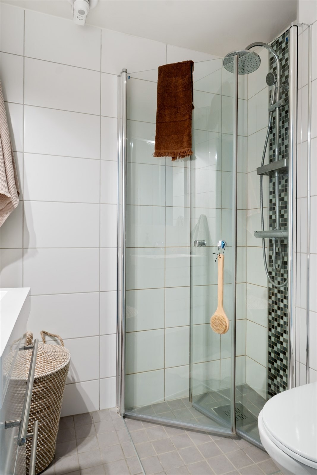 Dusjhjørne med glassdører og to-greps armatur fra Adora, vegghengt toalett fra Gustavsberg med innebygget sisterne. Galleribilde