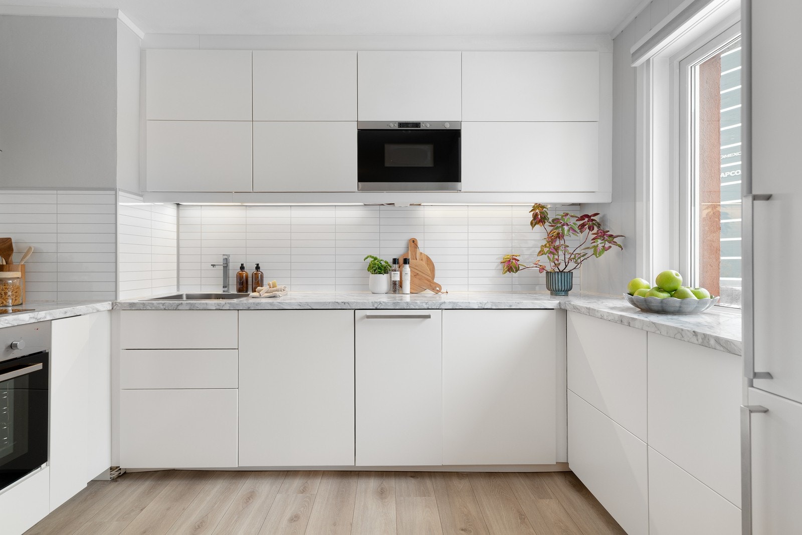 Stilrent IKEA-kjøkken fra 2015 med glatte fronter og laminert benkeplate med nedfelt stålkum. Galleribilde