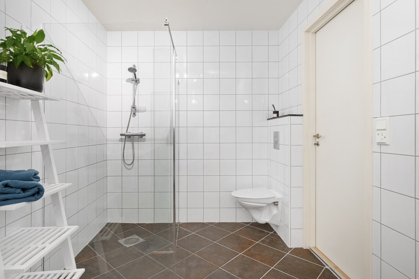 Badet er av god størrelse, innredet med hvite veggfliser og mørke gulvfliser for et delikat uttrykk. Galleribilde