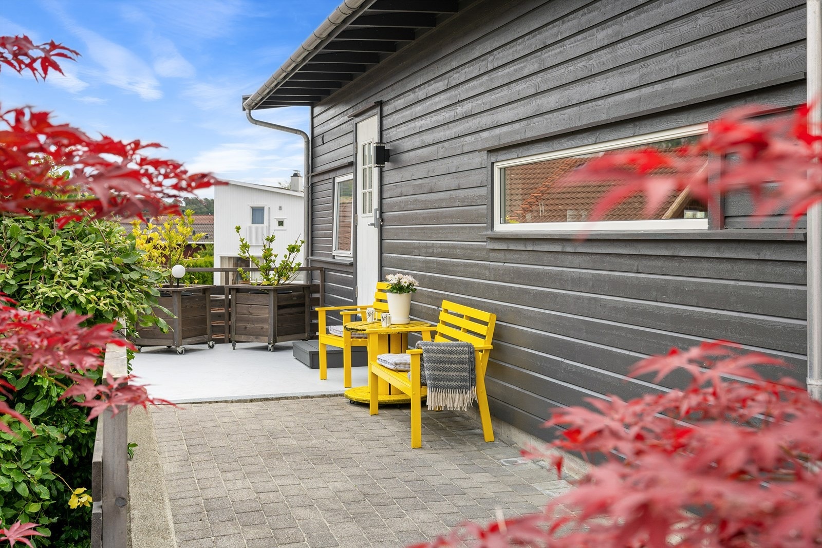 Ytterdøren er overbygd, på en steinlagt uteplass med belysning, ringeklokke og god plass til kafésett. Galleribilde