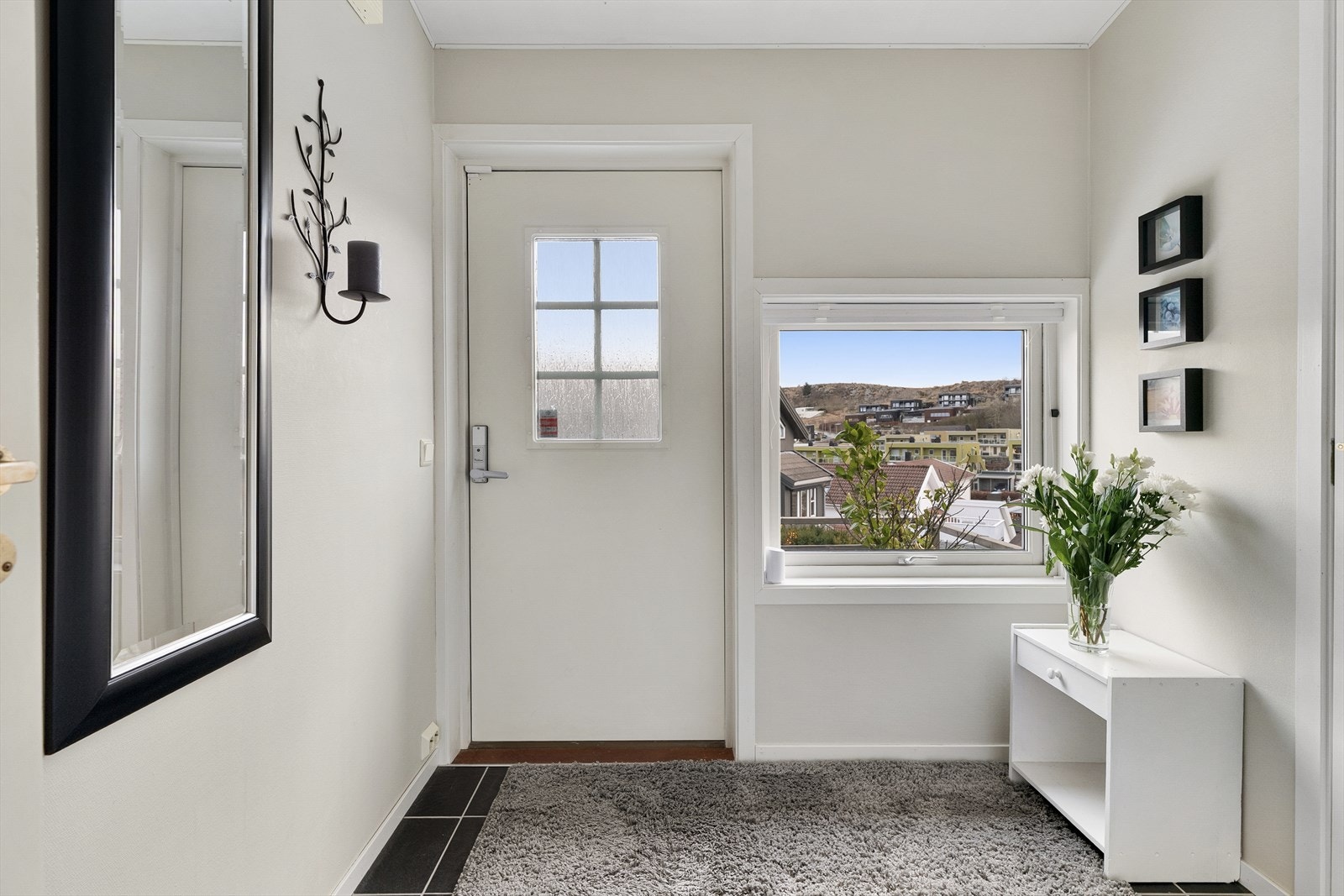 Entreen gir et godt førsteinntrykk med sorte gulvfliser og veggflater malt i lysegrått. I entreen er det plass til å henge fra seg yttertøyet, og flisene fortsetter inn på et praktisk gjestetoalett. Galleribilde