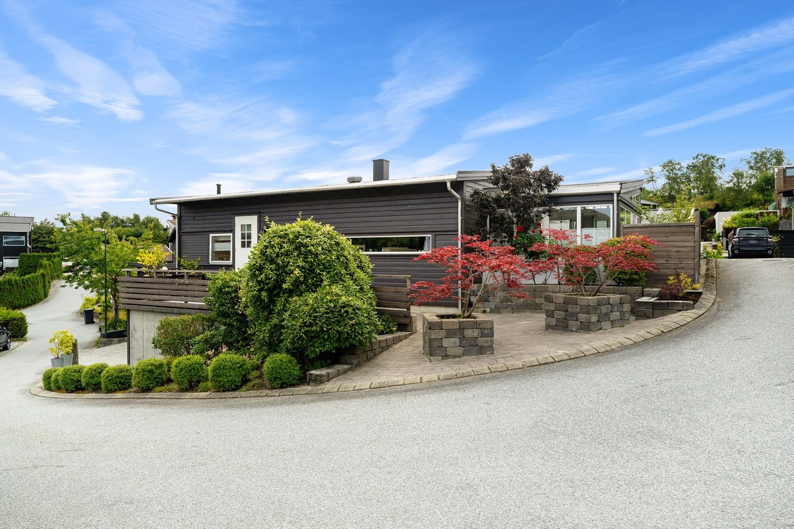 Tomten rammer inn huset med velstelte busker, blomster og epletrær. Galleribilde