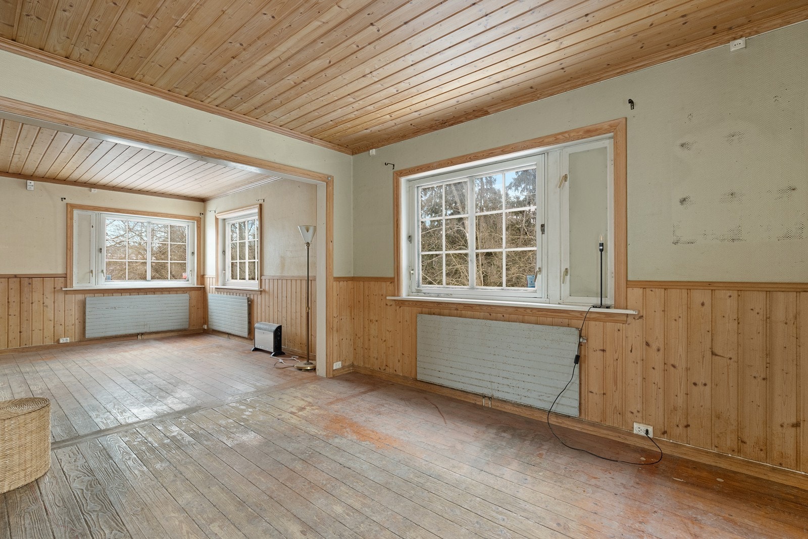 Stuen har panel i både vegger og tak, med store vindusflater som gir utsyn mot hagen. Galleribilde