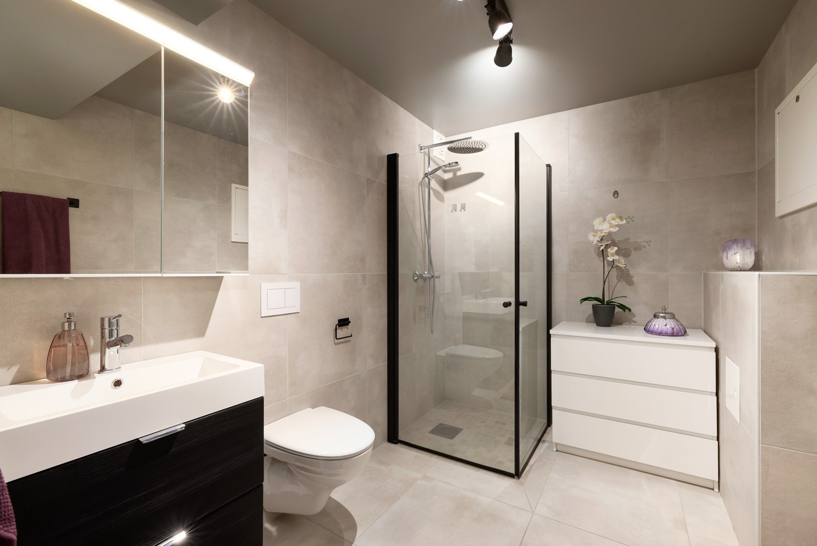 Badet er romslig og innredet med dusj, vegghengt toalett, servant med baderomsinnredning. Galleribilde