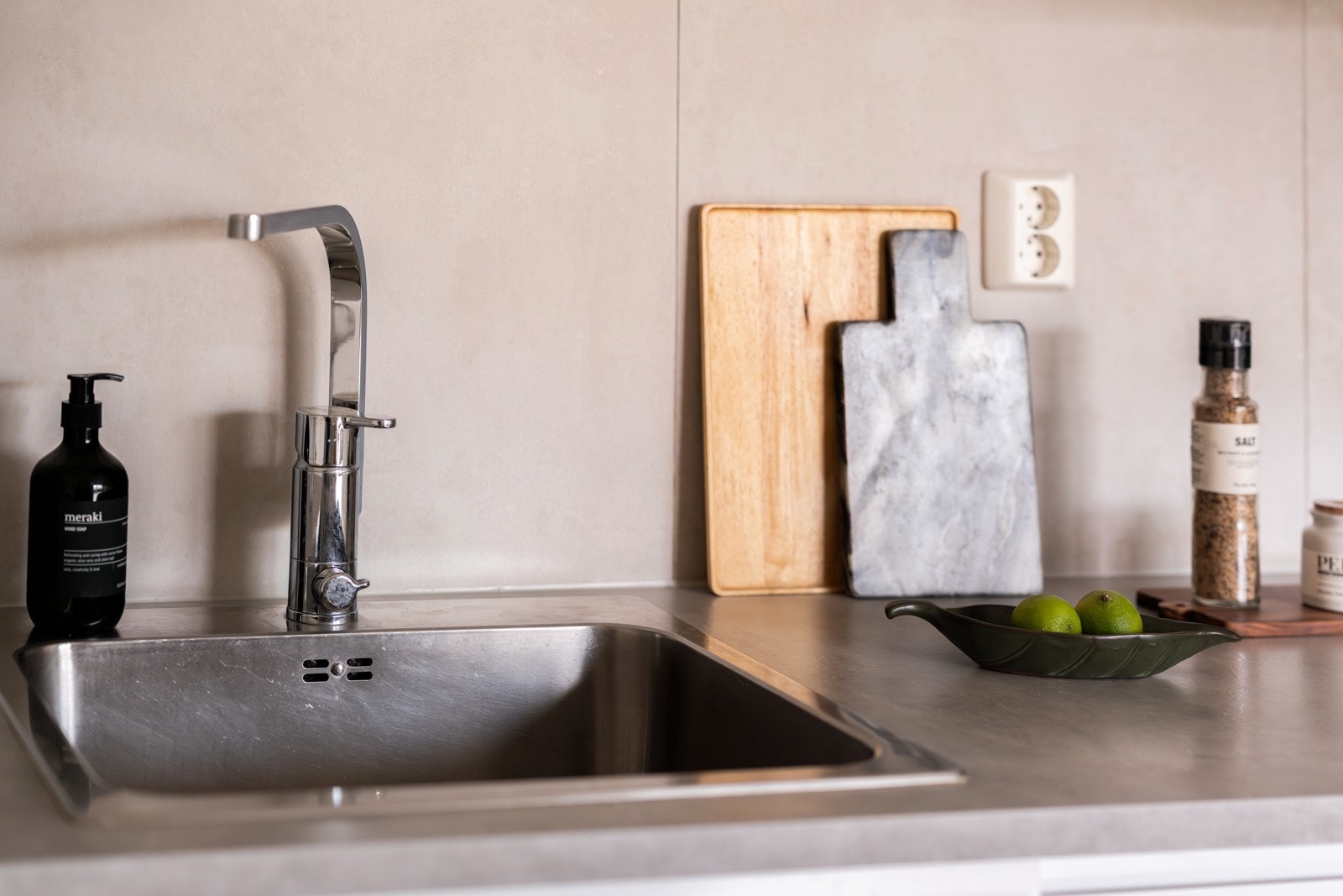 Innredningen har hvite glatte fronter med soft-close og laminert benkeplate med nedfelt oppvaskkum. Praktisk med fliser i benkeryggen og belysning under overskap. Det er også montert komfyrvakt ved platetoppen. Galleribilde