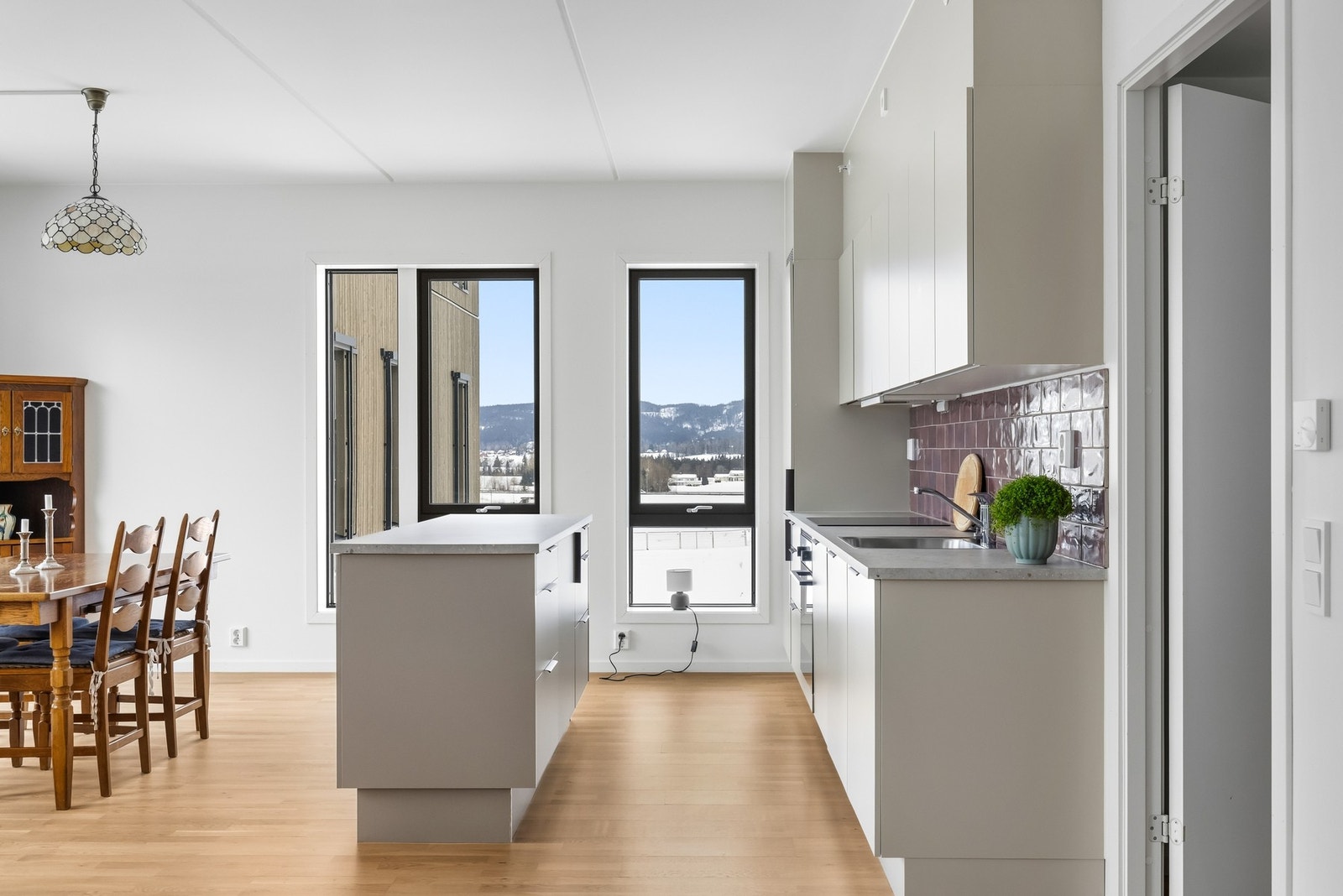 Kjøkkenet har slette beige fronter som gir kjøkkenet et moderne uttrykk, benkeplate i slitesterk laminat og integrerte hvitevarer som platetopp, oppvaskmaskin, stekeovn og kjøleskap med frysedel. Galleribilde