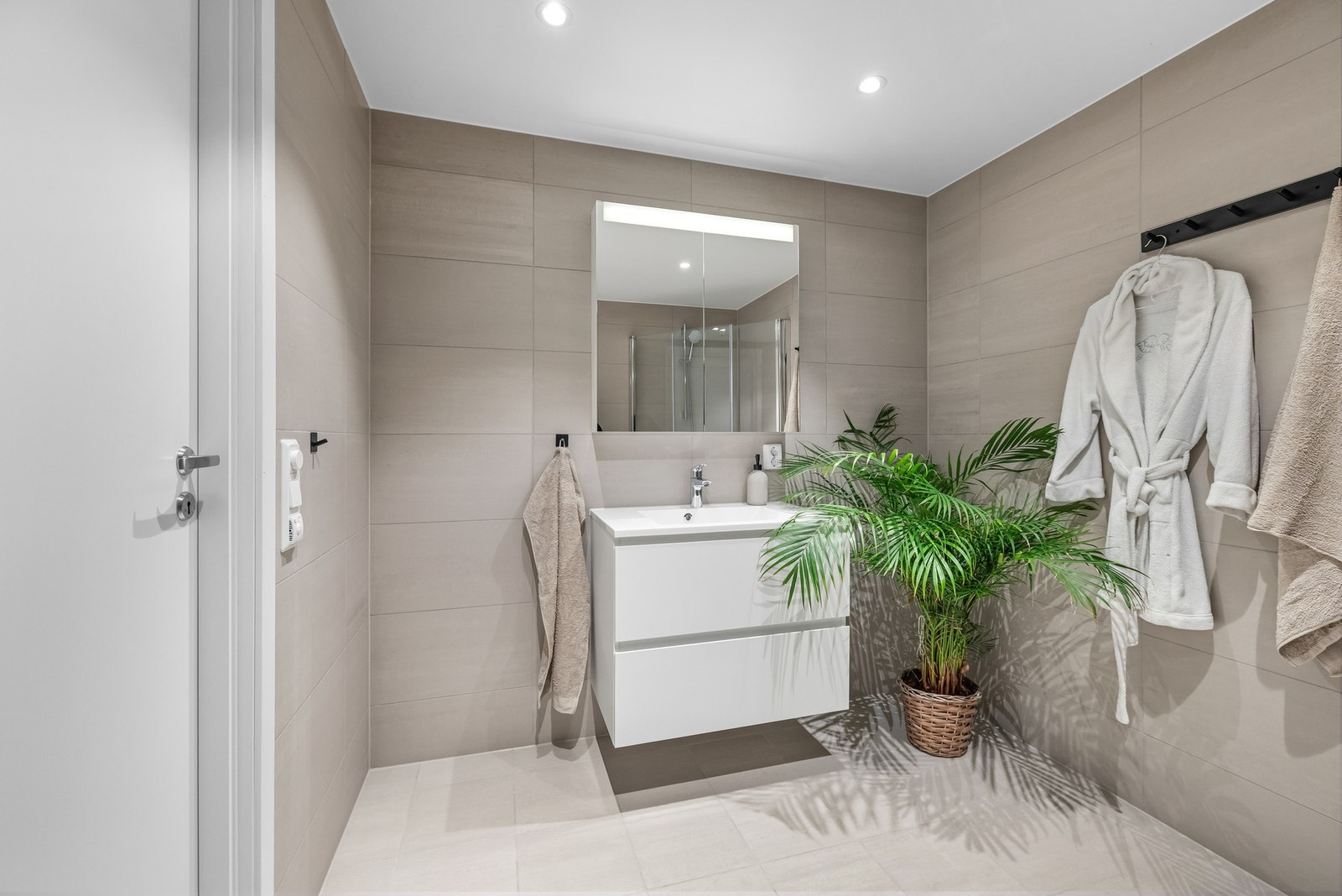 Baderommet er delikat med fliser på gulv og vegger og downlights i taket for optimal belysning. Galleribilde