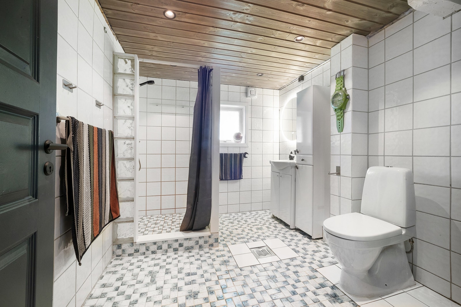 Flislagt bad av eldre dato, med gulvvarme og himling utført i trepanel med downlights Galleribilde