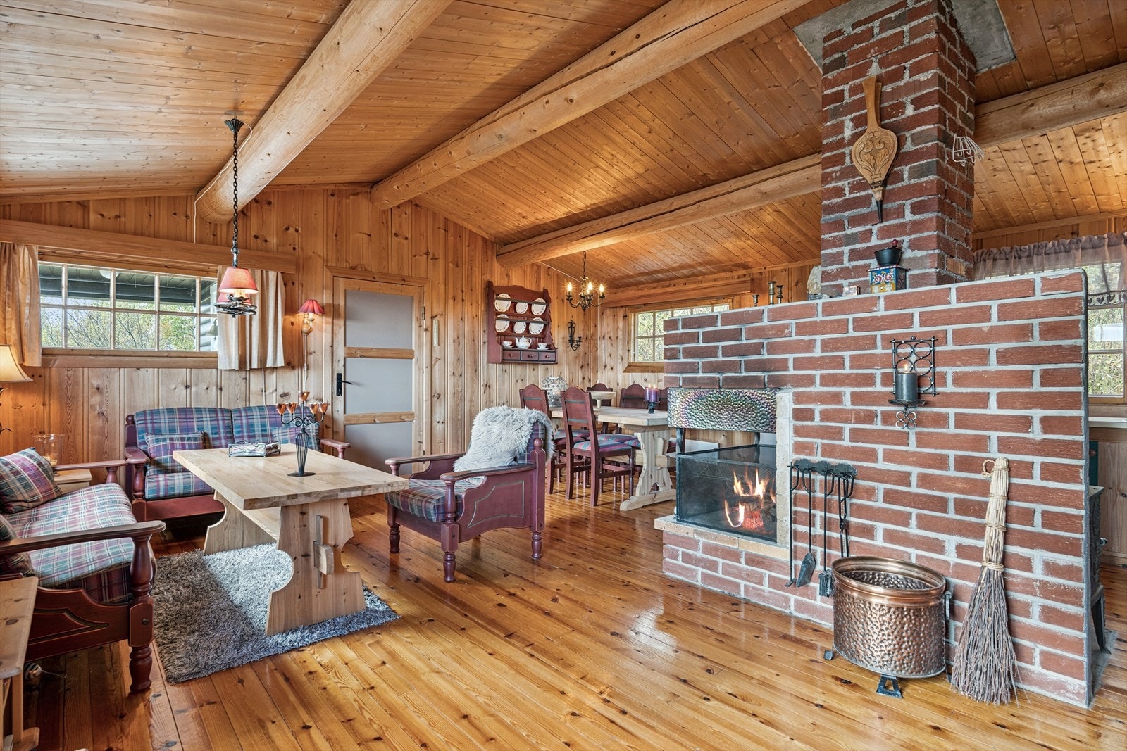 Rommet har mønet himling med flotte tømmeråser og en stor, åpen teglsteinspeis fungerer som romdeler inn mot kjøkken. Galleribilde