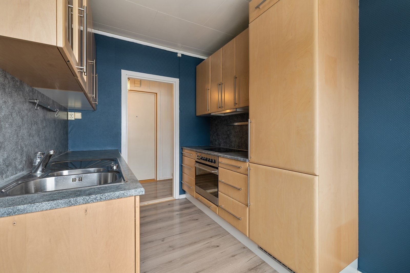 Kjøkkenet har glatte fronter og laminat benkeplate. Det er integrert platetopp, stekeovn og kombiskap (kjøl/frys) Galleribilde