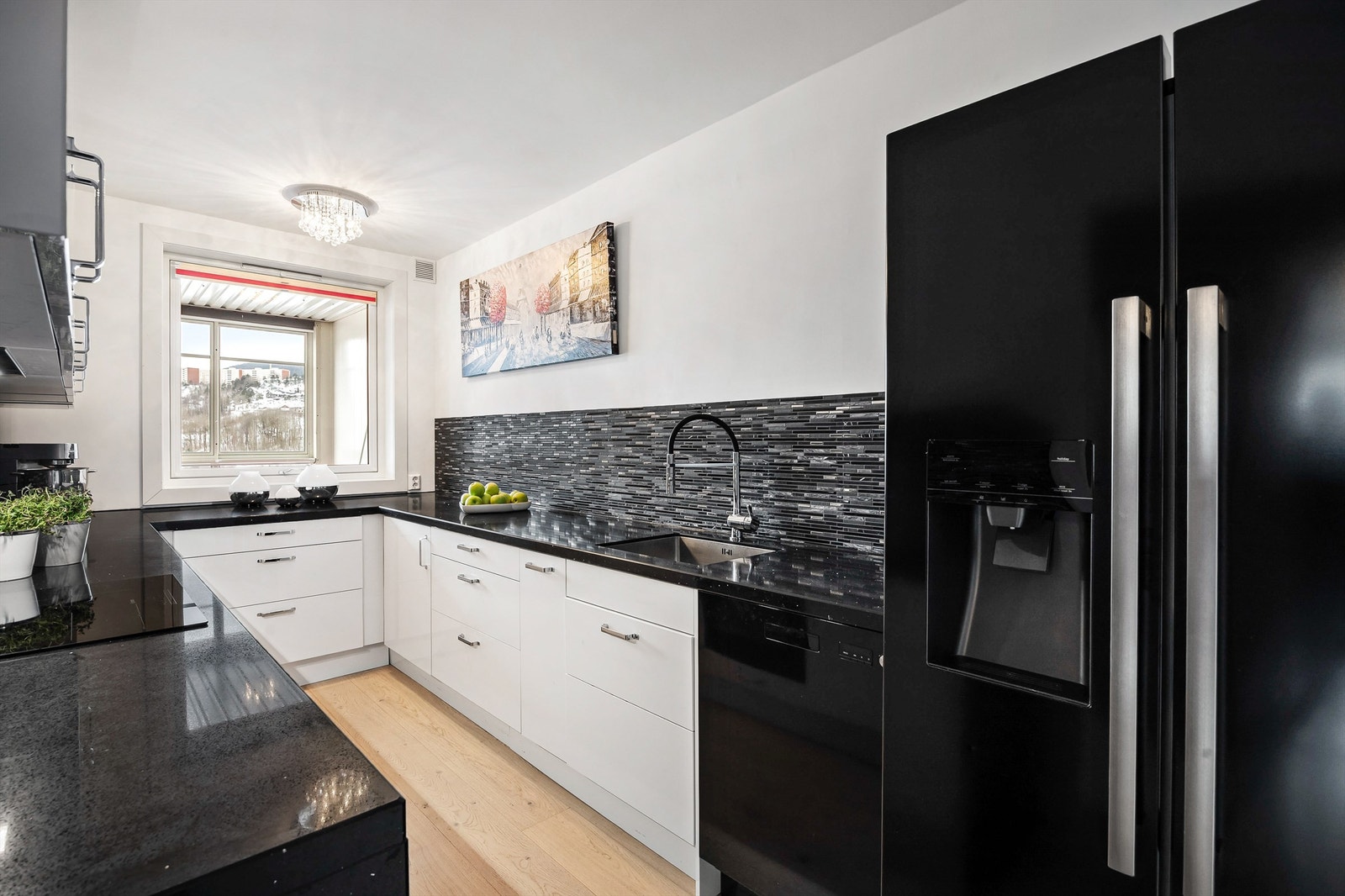 Kjøkkeninnredningen har hvite høyglansfronter og flislagte felt over benkeplatene. Galleribilde